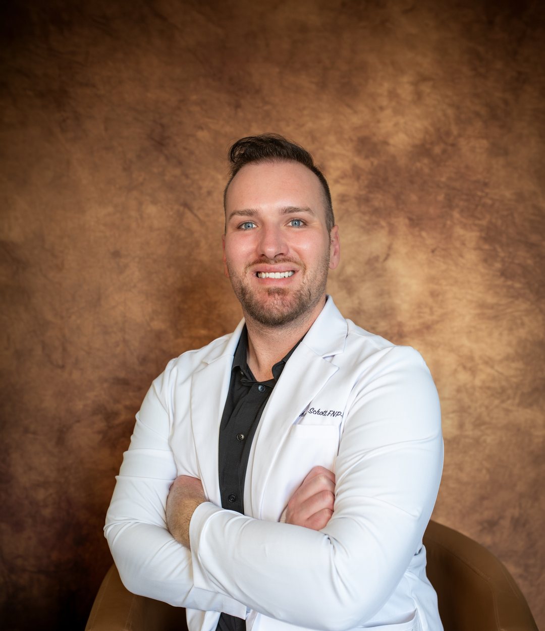 A studio headshot of a nurse practitioner in a white coat