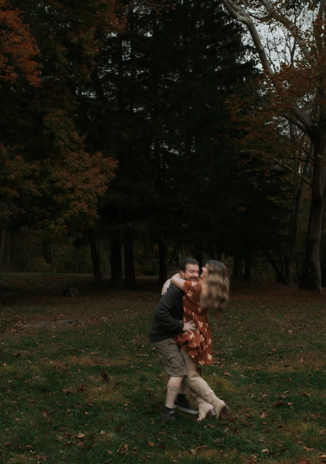 A couple spinning together in an autumn field, caught mid-motion