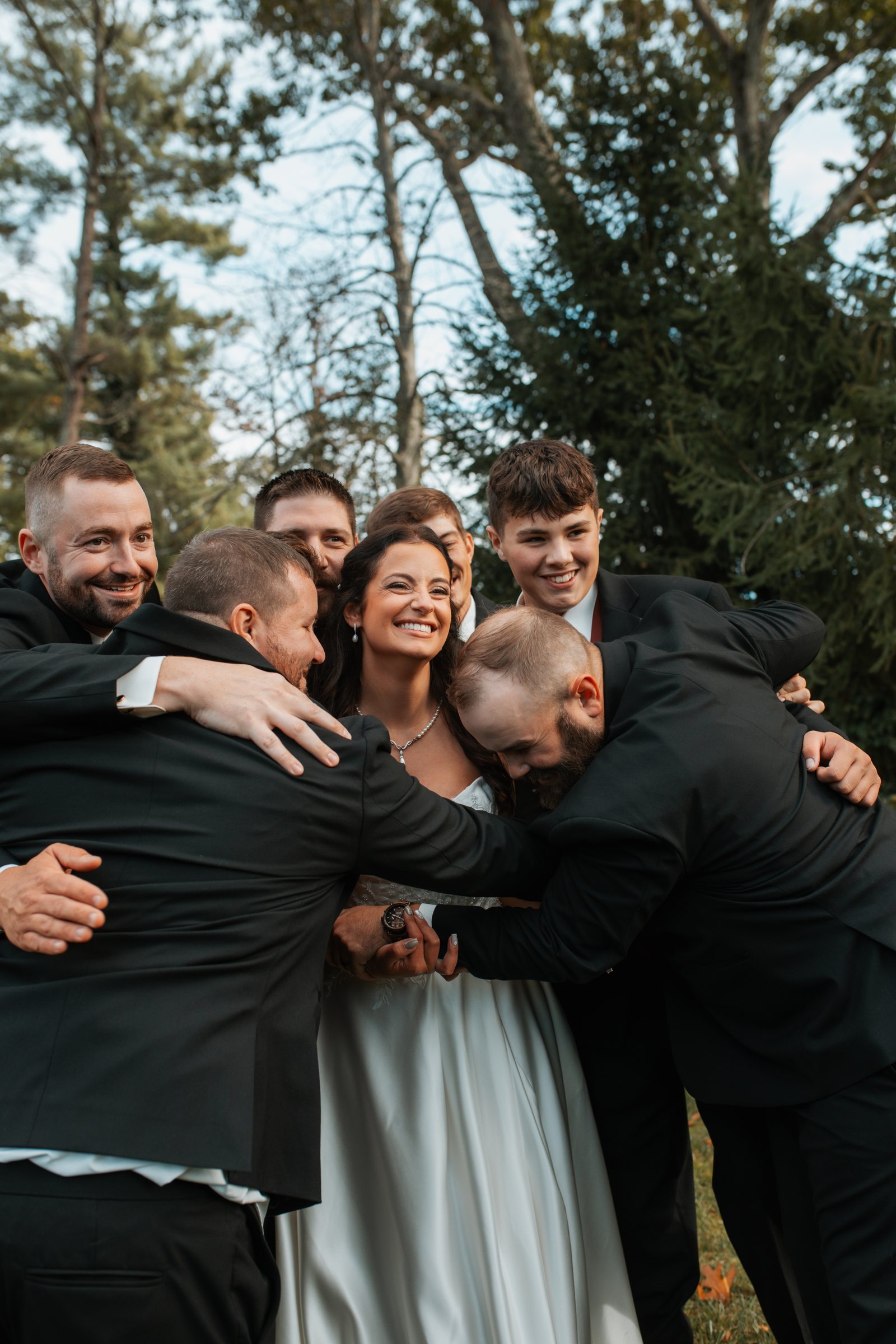 A bride laughing in the middle of a group hug with the wedding party